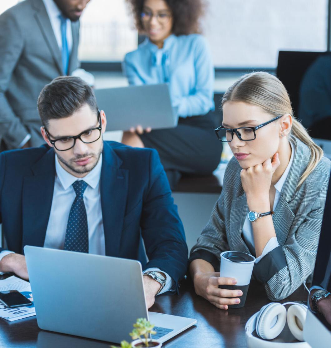 multicultural businesspeople looking at laptops in workspace